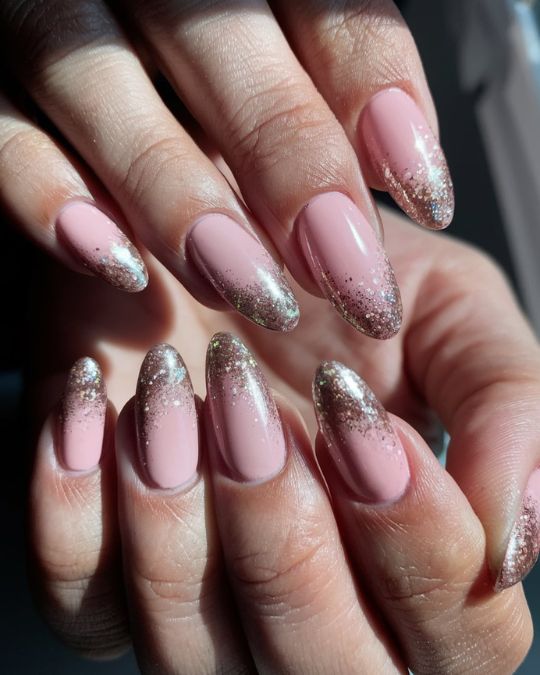 Gel manicure almond-shaped nails. The nails feature a two-tone glitter ombré design where pink and champagne goldsilver glitter colors are blended together