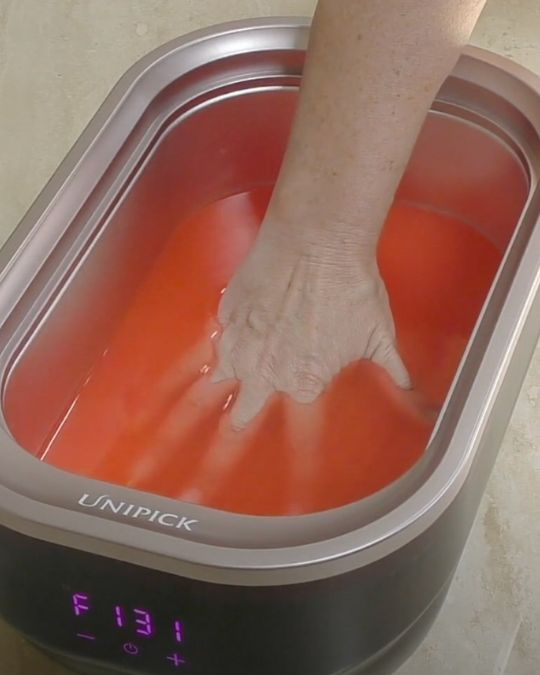 hands are dipped into warm paraffin wax treatment