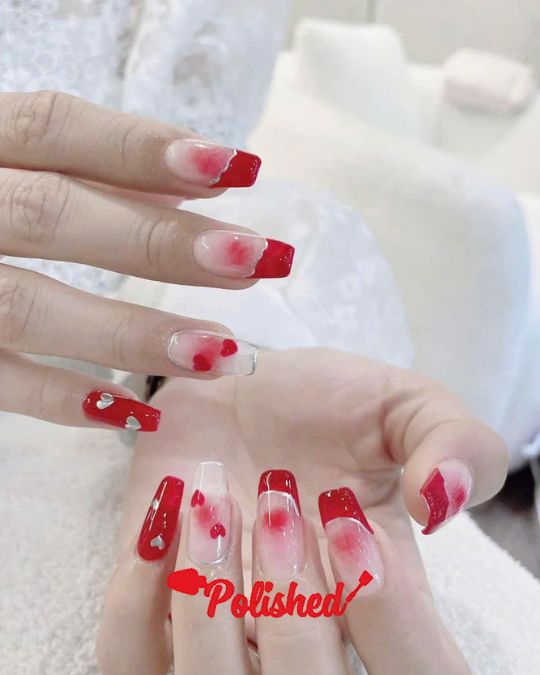 Square-tipped nails with a gradient from clear to vibrant red, featuring delicate heart designs