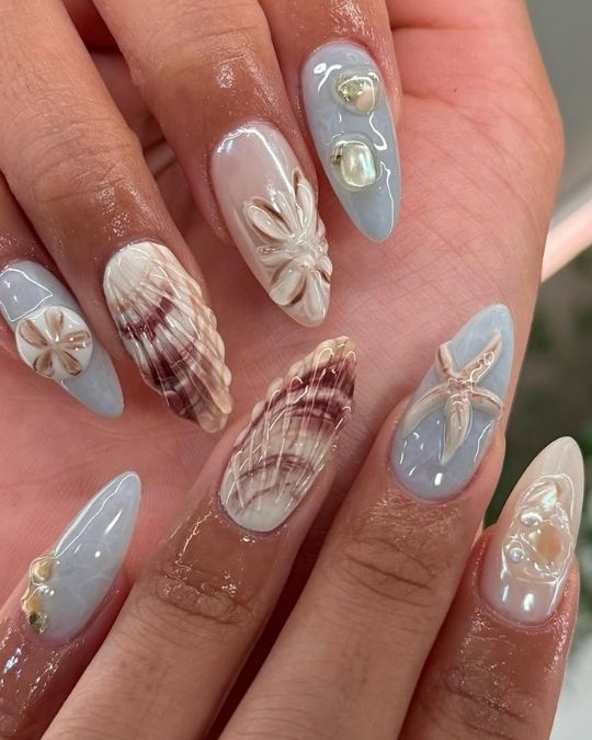Pearlescent shells, soft blue hues, and shimmering accents on almond nails