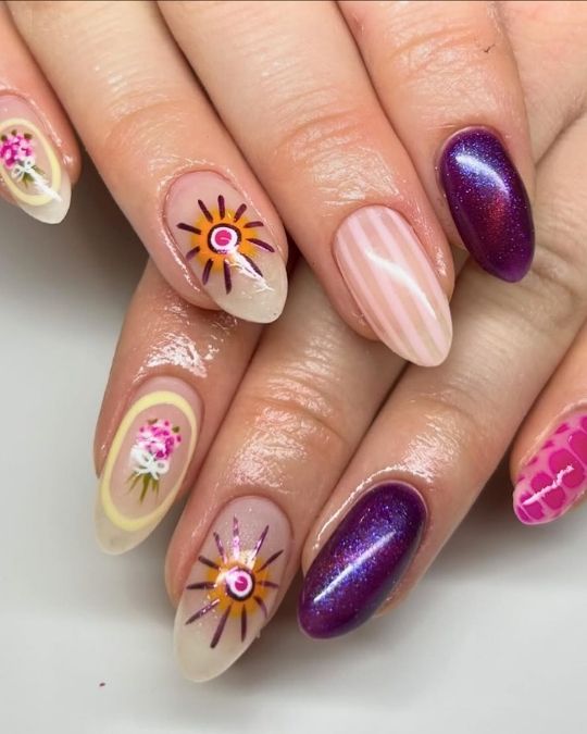 Eclectic almond nails featuring sunbursts, floral designs, and shimmering purple accents.