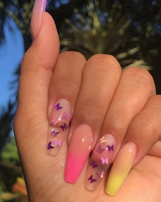 Pink and yellow ombré tips alternate with butterfly stickers on sheer base nails