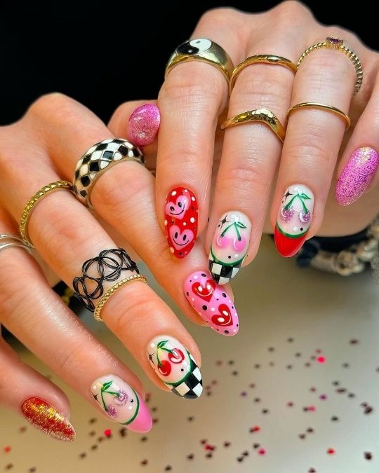 Cherry and smiley heart nails with checkered tips and glitter accents.