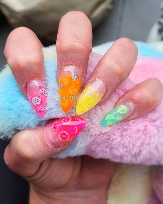 Stiletto nails featuring colorful fruit designs - dragonfruit, orange, lemon, lime.