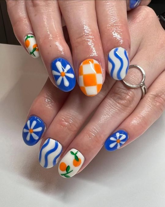 short round nails with bright blue daisies, orange checkers, and cute little citrus fruits