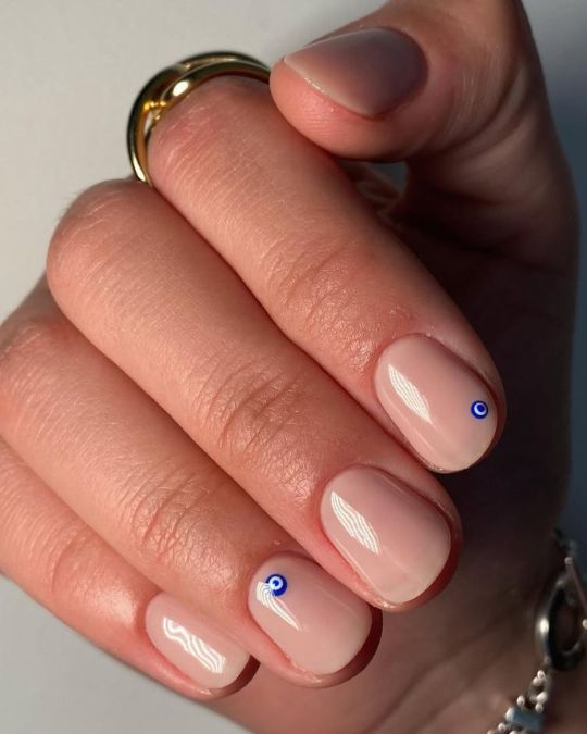 short round nails with nude base and evil eyes