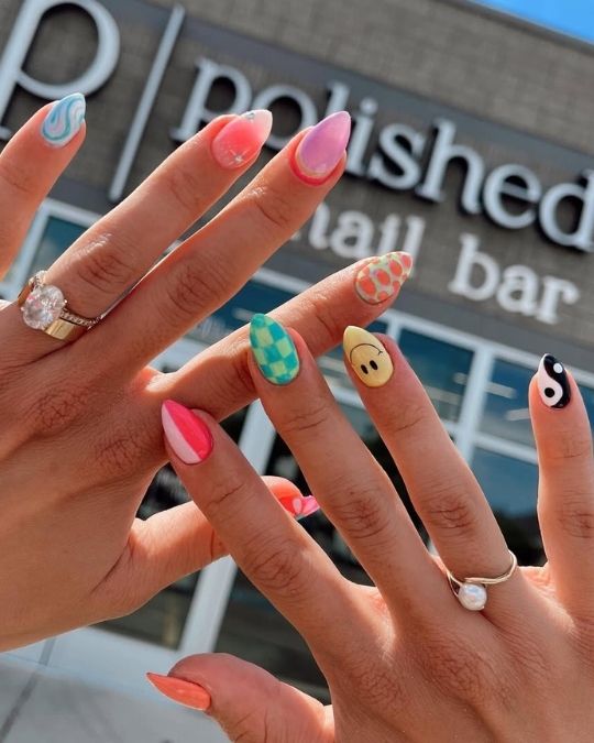 Mixed design nails with smiley face, yin-yang, checkers, and swirls.