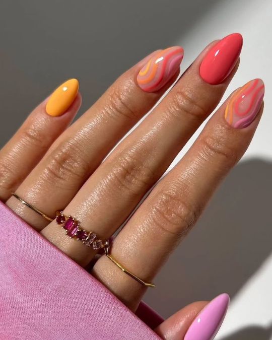 almond-shaped nails with mix of orange, coral, and pink with swirl designs