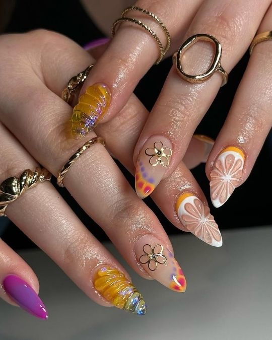 Whimsical almond nails featuring floral designs, citrus patterns, and golden accents.
