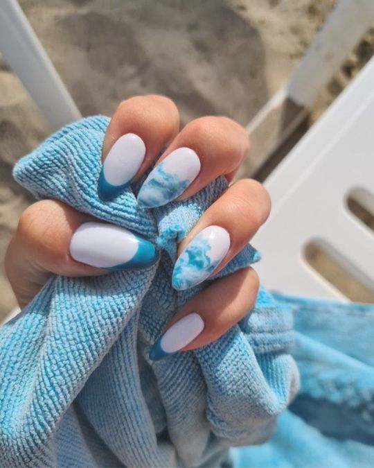 Crisp white base with swirling blue marble and French tips almond nails